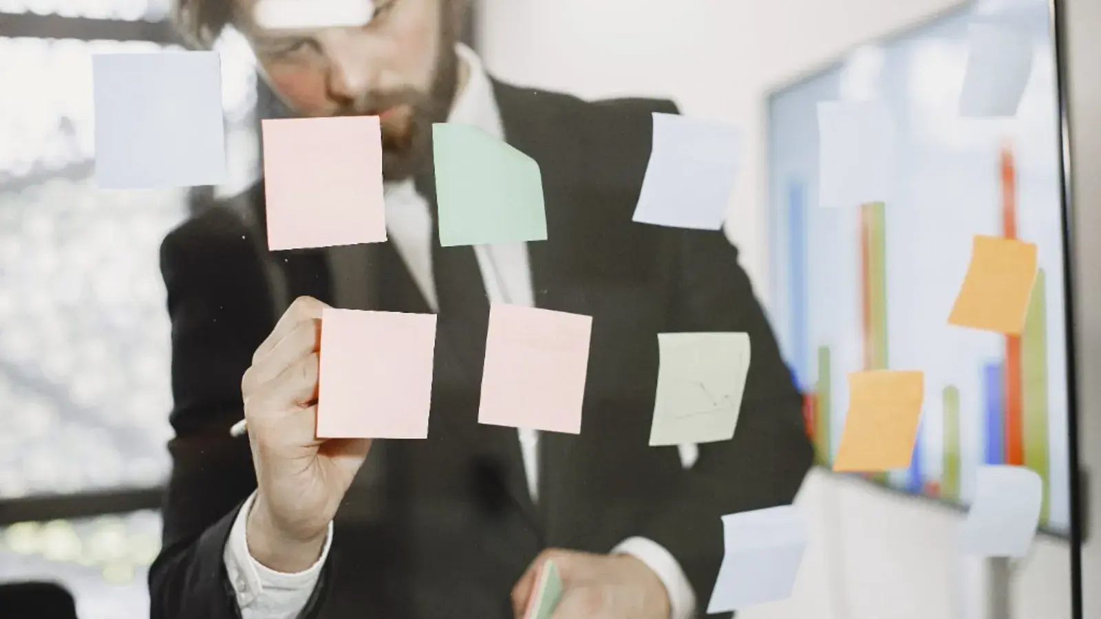 Professional organising analysis notes on a glass board with data charts in the background